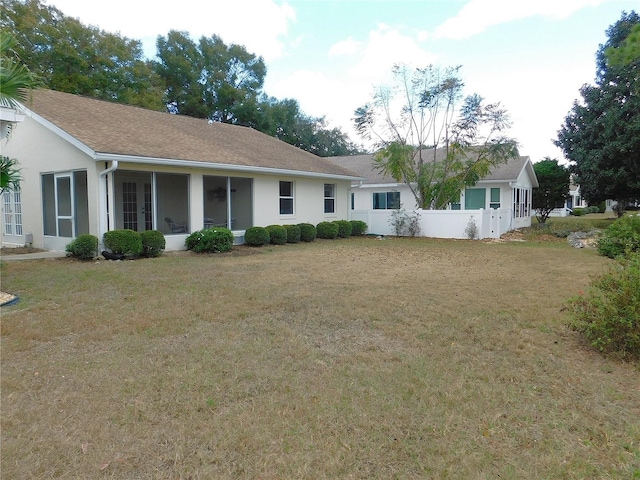 rear view of house with a lawn and a sunroom