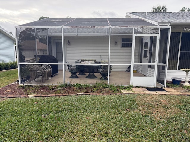 back of property featuring a yard, glass enclosure, and a patio area