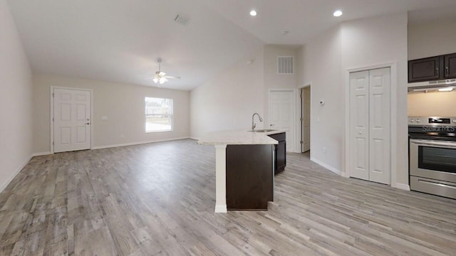 kitchen with high vaulted ceiling, stainless steel electric stove, sink, ceiling fan, and an island with sink