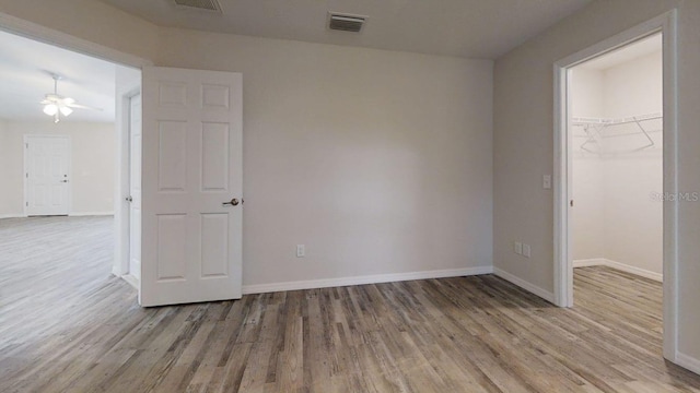 unfurnished bedroom featuring light wood-type flooring, a walk in closet, and a closet