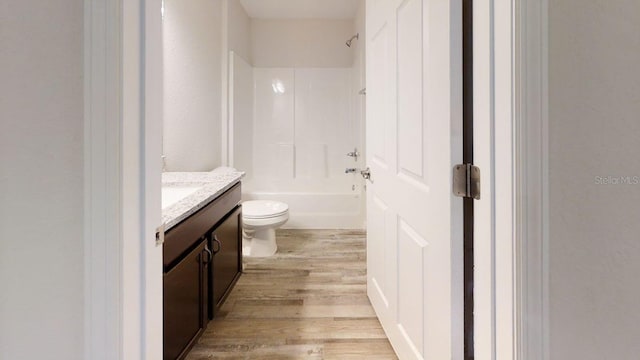 full bathroom with hardwood / wood-style flooring, vanity, toilet, and washtub / shower combination