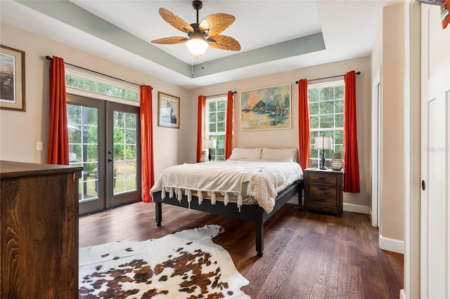 bedroom featuring dark hardwood / wood-style flooring, access to exterior, a raised ceiling, and french doors