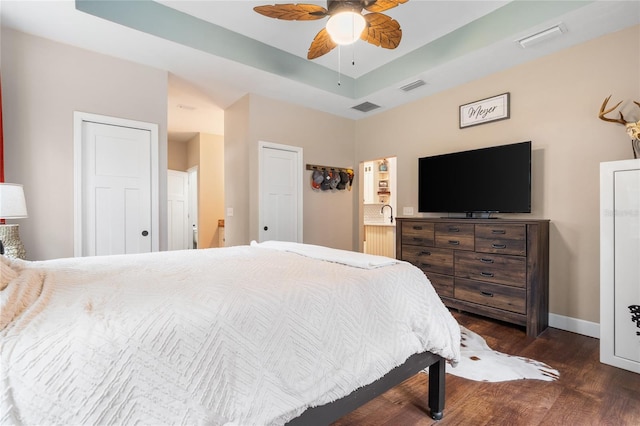 bedroom featuring dark hardwood / wood-style flooring, a raised ceiling, and ceiling fan