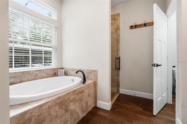 bathroom featuring shower with separate bathtub, hardwood / wood-style floors, and toilet