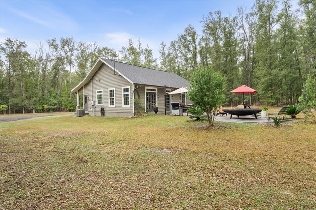 view of front of property featuring a fire pit, a front lawn, central air condition unit, and a patio area