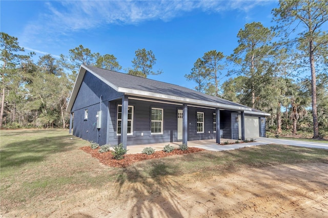 view of front of property featuring covered porch, a front yard, and a garage