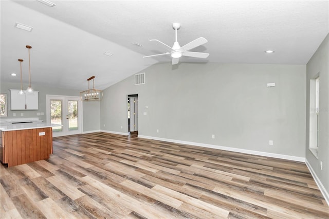 kitchen featuring lofted ceiling, white cabinetry, french doors, hanging light fixtures, and light wood-type flooring