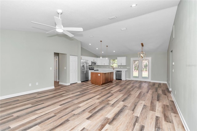 unfurnished living room with ceiling fan, lofted ceiling, french doors, and light wood-type flooring