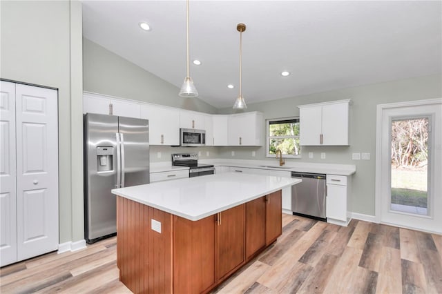 kitchen featuring stainless steel appliances, a kitchen island, pendant lighting, white cabinets, and sink