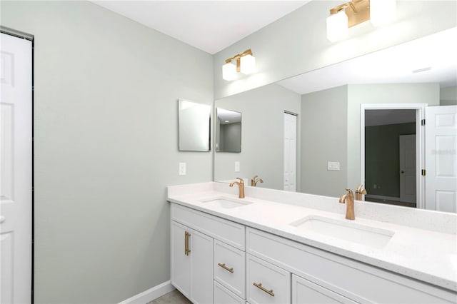 full bath featuring a sink, baseboards, and double vanity