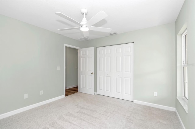 unfurnished bedroom featuring ceiling fan, light colored carpet, and a closet