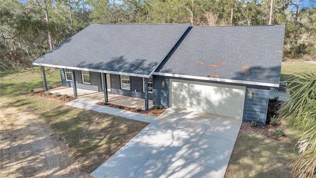 view of front facade featuring covered porch, an attached garage, concrete driveway, and a front lawn