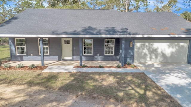 view of front facade with a porch, concrete driveway, roof with shingles, a front yard, and a garage