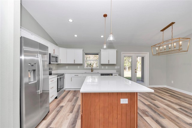 kitchen featuring light wood-style flooring, a sink, a center island, stainless steel appliances, and french doors