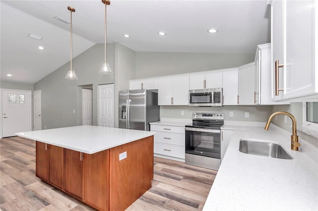 kitchen with a kitchen island, a sink, light countertops, appliances with stainless steel finishes, and light wood-type flooring