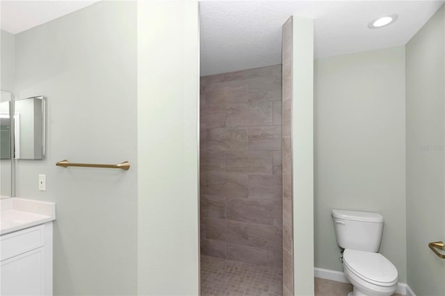 bathroom featuring vanity, baseboards, recessed lighting, a tile shower, and toilet