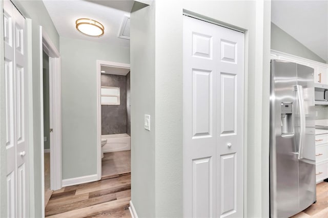 hallway featuring baseboards and light wood finished floors