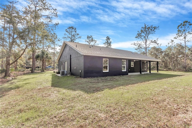 rear view of house featuring stucco siding, a patio, a yard, and central AC unit