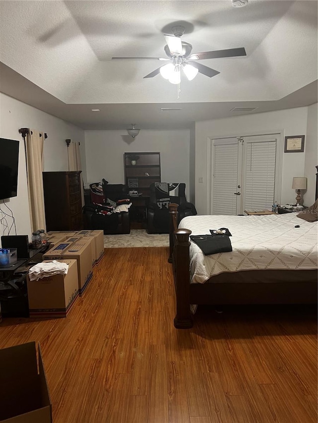 bedroom featuring a tray ceiling, ceiling fan, and wood-type flooring