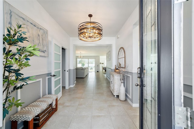 hall with light tile patterned flooring and a notable chandelier