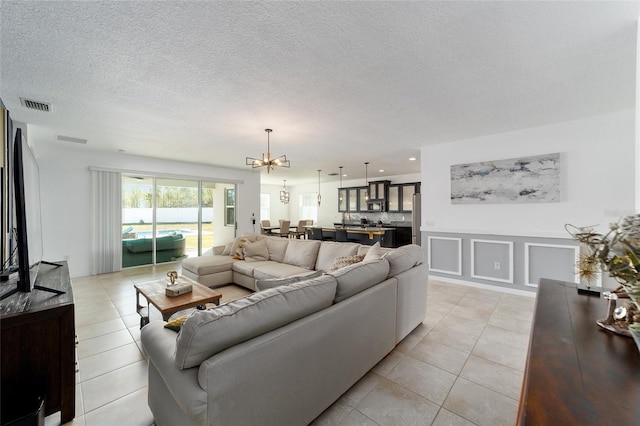 living room featuring light tile patterned floors, a chandelier, and a textured ceiling