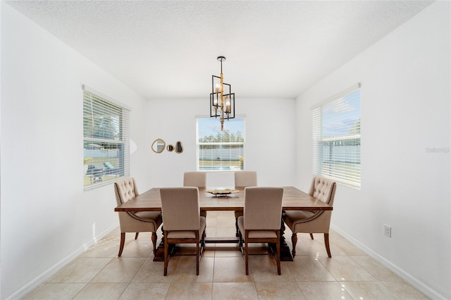 tiled dining space featuring a notable chandelier and a textured ceiling