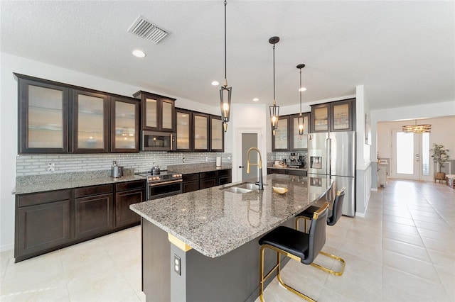 kitchen with decorative light fixtures, sink, stainless steel appliances, and a center island with sink