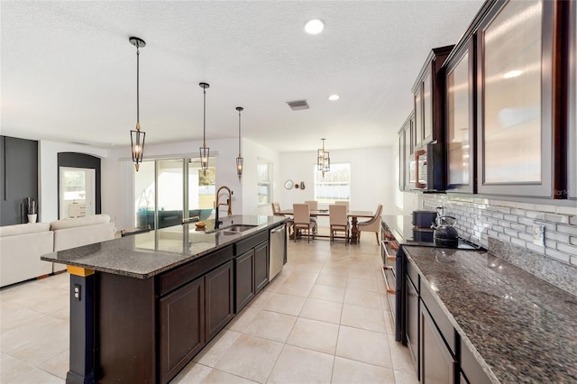 kitchen featuring hanging light fixtures, sink, an island with sink, appliances with stainless steel finishes, and dark brown cabinetry