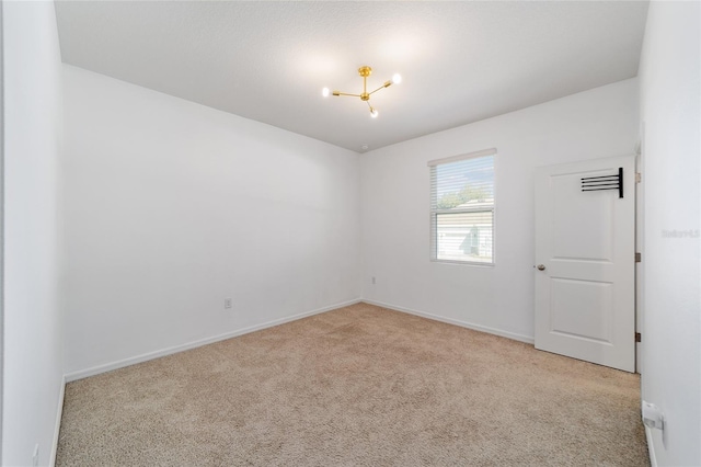 spare room featuring light carpet and a chandelier