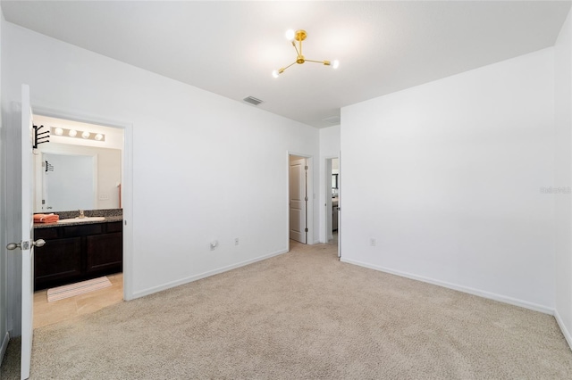 unfurnished bedroom featuring ensuite bathroom, sink, and light carpet