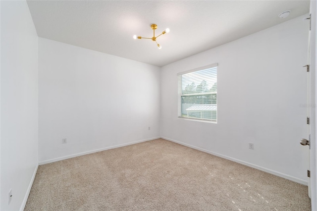 unfurnished room featuring light colored carpet and a notable chandelier