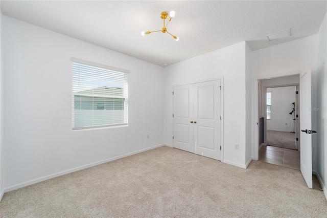 unfurnished bedroom featuring a chandelier, a closet, and light colored carpet