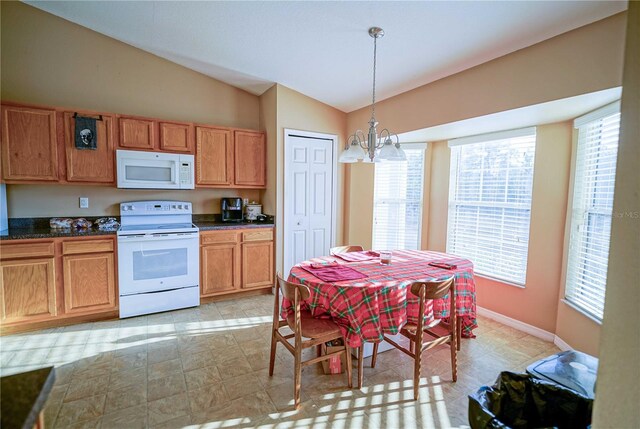 kitchen featuring vaulted ceiling, hanging light fixtures, white appliances, and an inviting chandelier