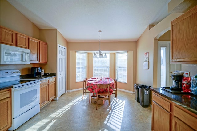 kitchen with a textured ceiling, pendant lighting, white appliances, and a notable chandelier