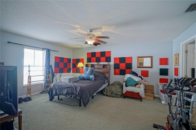 carpeted bedroom with ceiling fan and a textured ceiling