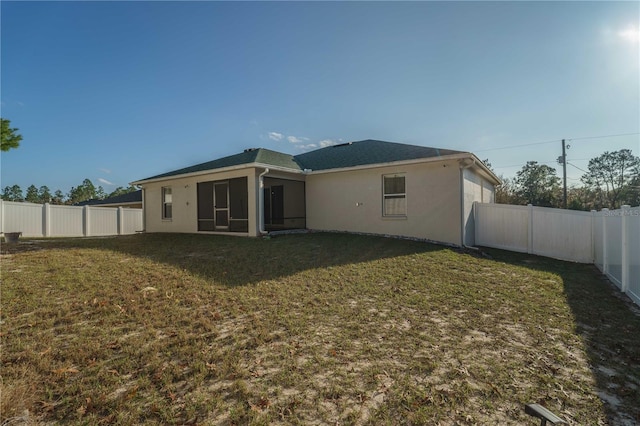 rear view of house with a sunroom and a yard