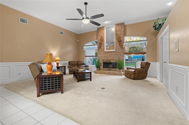 living room with light colored carpet, a brick fireplace, ceiling fan, and crown molding