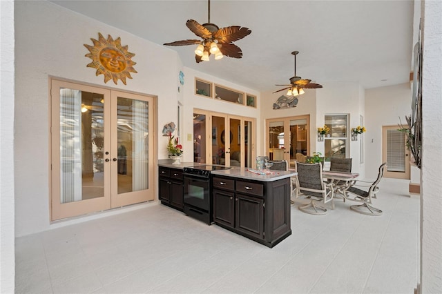 kitchen featuring kitchen peninsula, french doors, ceiling fan, black electric range oven, and light tile patterned flooring