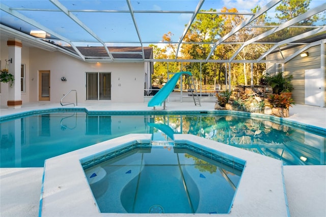 view of pool featuring a patio, glass enclosure, an in ground hot tub, and a water slide