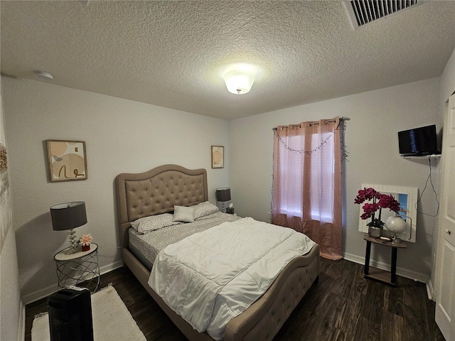 bedroom with dark wood finished floors, visible vents, baseboards, and a textured ceiling