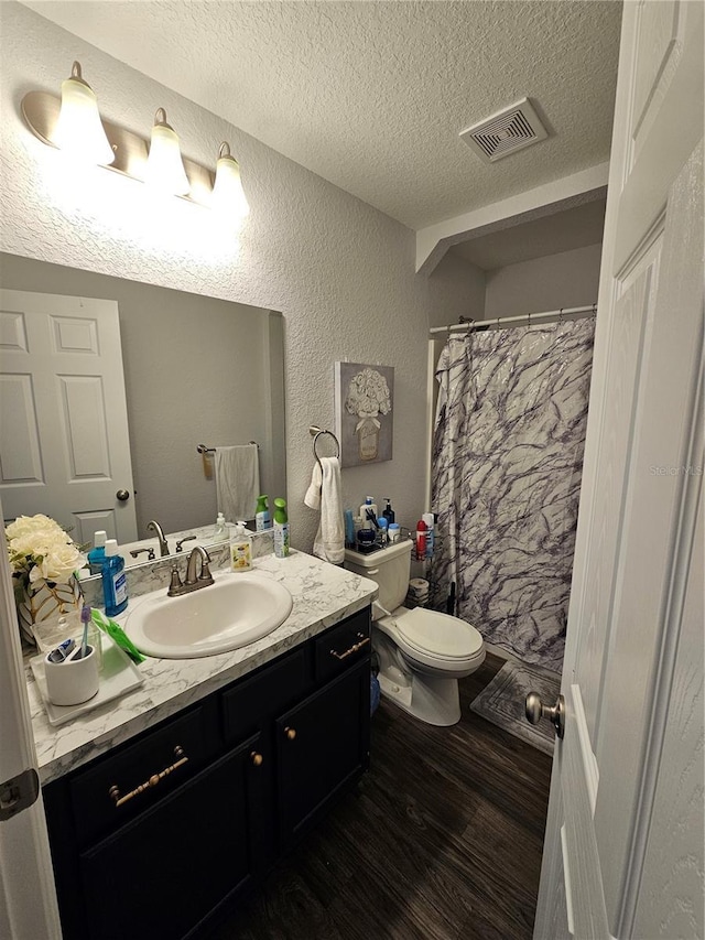 full bath with visible vents, toilet, a textured ceiling, wood finished floors, and vanity