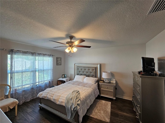 bedroom featuring visible vents, baseboards, dark wood finished floors, a textured ceiling, and a ceiling fan