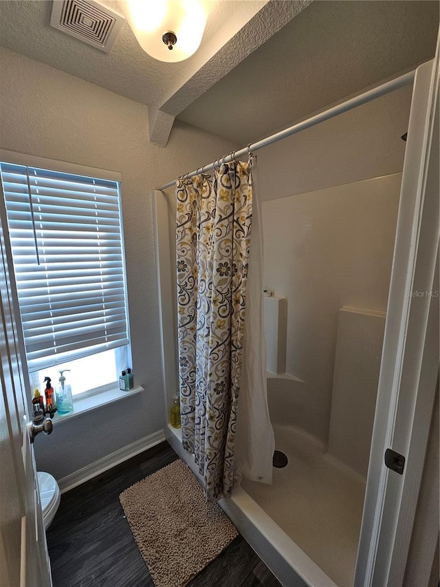 bathroom featuring wood finished floors, visible vents, baseboards, a shower stall, and toilet