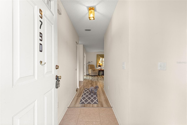 hallway featuring light tile patterned floors and a textured ceiling