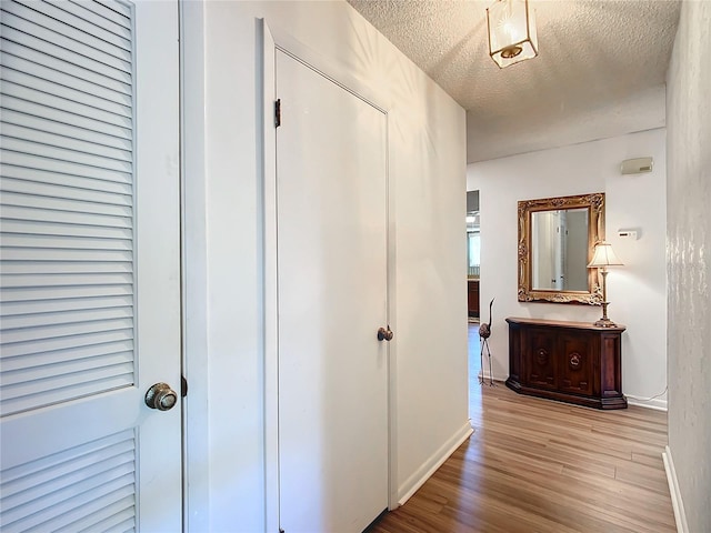 corridor featuring light hardwood / wood-style floors and a textured ceiling