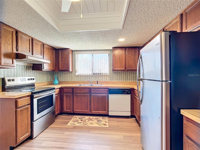 kitchen with stainless steel appliances, light hardwood / wood-style flooring, ceiling fan, and sink