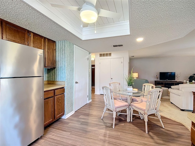 dining area with ceiling fan, a textured ceiling, and light wood-type flooring