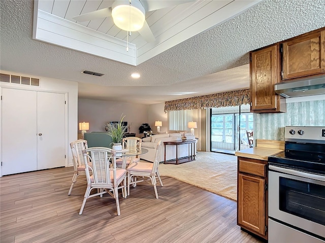 dining room with ceiling fan, a textured ceiling, and light hardwood / wood-style flooring