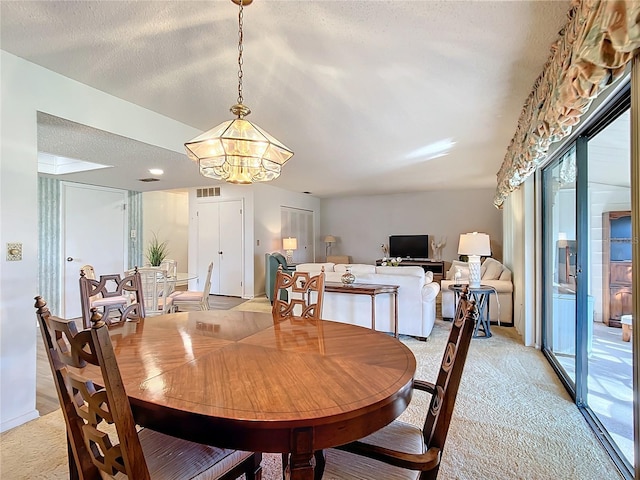 dining room featuring light carpet, a textured ceiling, and a notable chandelier