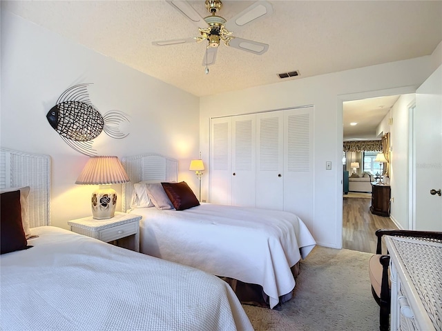 bedroom featuring a textured ceiling, a closet, light hardwood / wood-style flooring, and ceiling fan